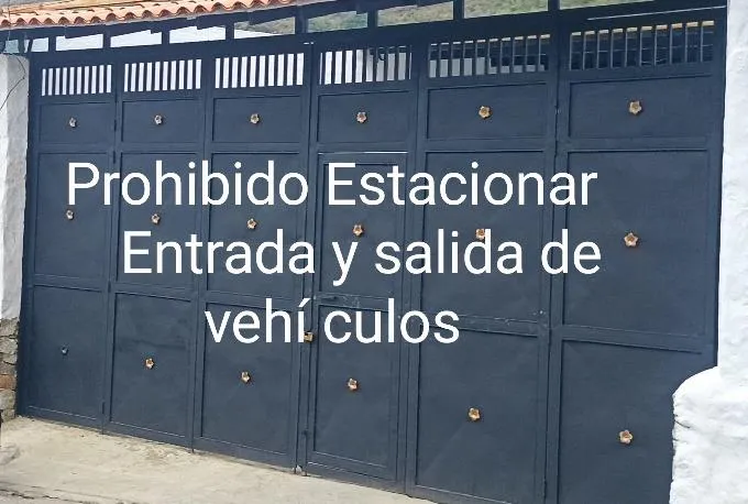El famoso portón de doble hoja: «Prohibido Estacionar. Entrada y salida de vehículos», con la división justo donde no debía estar.