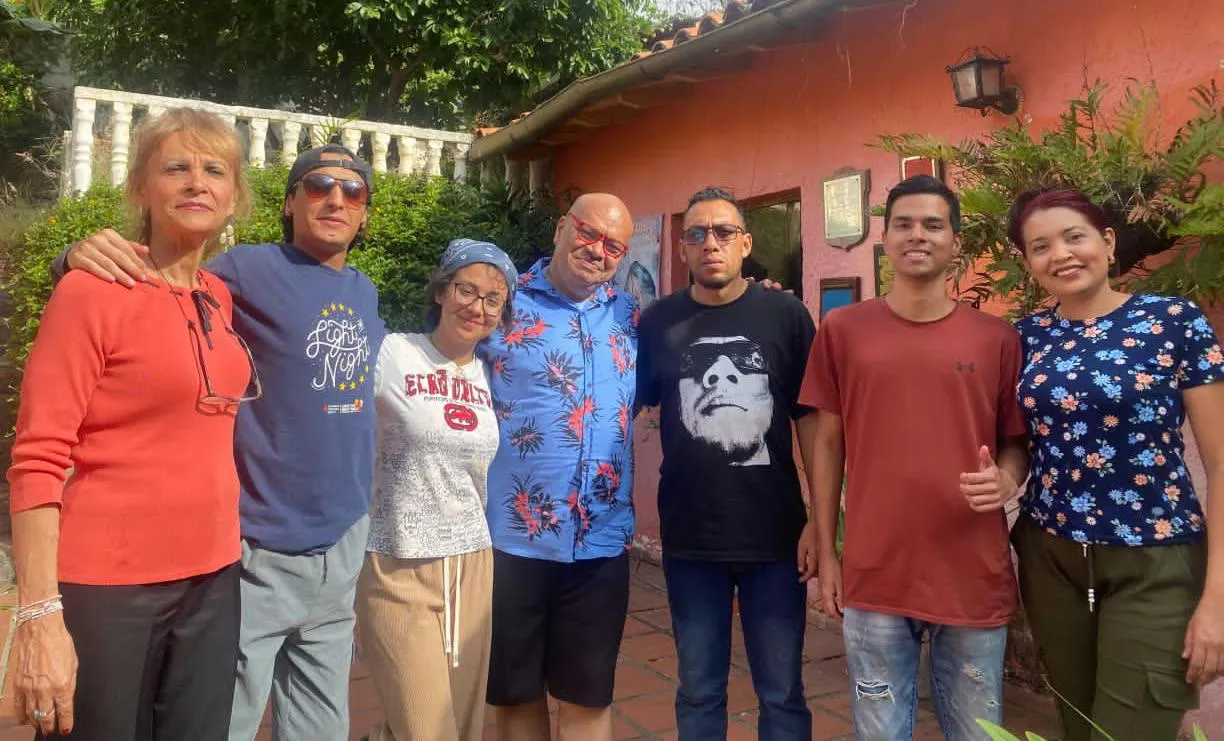 Parte del equipo del taller y del cortometraje «Muñecas Rotas», reunido frente a una casa de paredes rosadas y tejas.