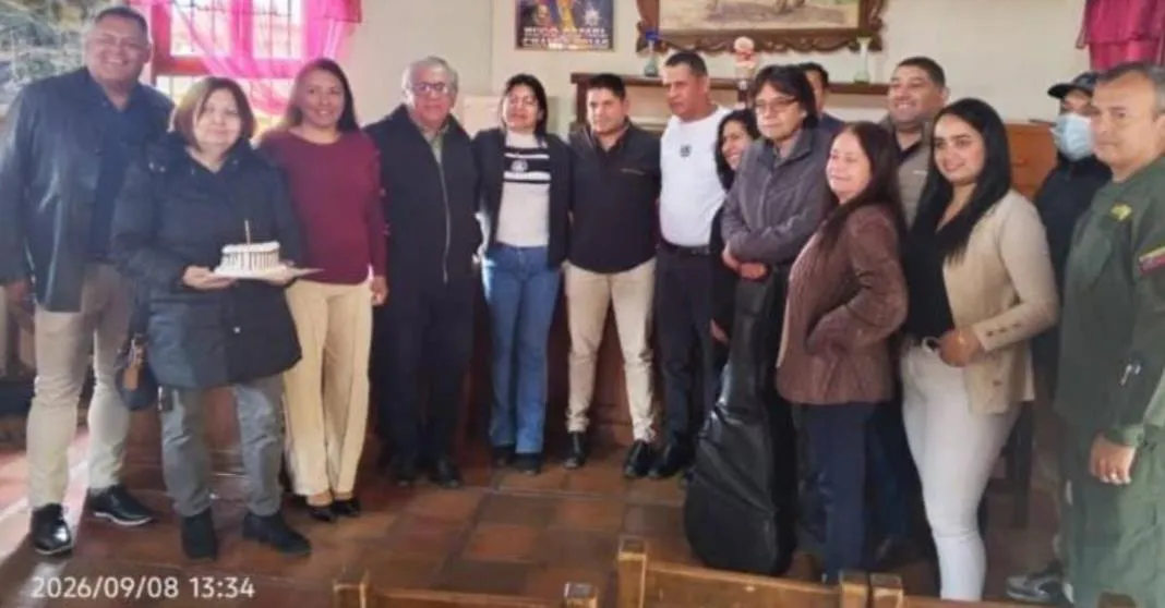 Retrato de grupo de los asistentes al homenaje, con la torta en primer plano.