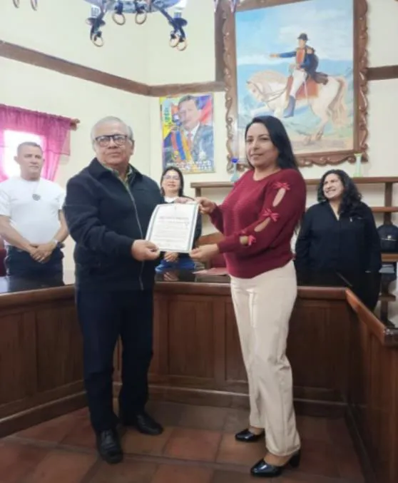 Entrega del pergamino del reconocimiento en el salón del Concejo Municipal de Pueblo Llano, bajo el cuadro del Libertador a caballo.