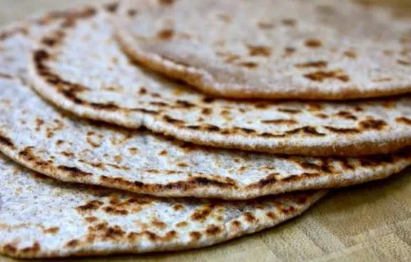 Arepas de trigo recién asadas, delgadas y con las manchas del budare, apiladas y todavía espolvoreadas de harina.