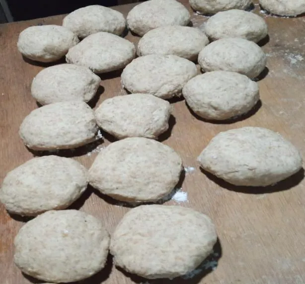 Las bolas de masa de trigo, ya aplanadas y puestas en hileras sobre la mesa de madera, esperando el budare.