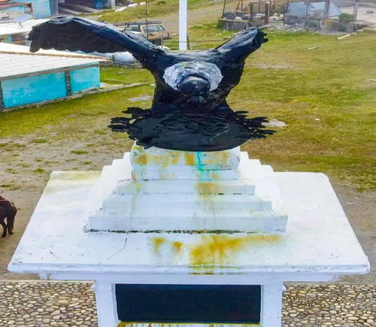 La escultura del cóndor andino sobre el pedestal del monumento, con manchas de pintura amarilla en la piedra.