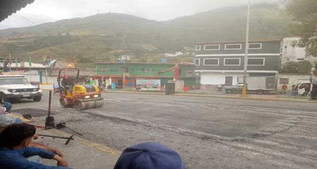 La calle en obras: los trabajadores extendiendo la capa de asfalto y la maquinaria amarilla detenida en el cruce.