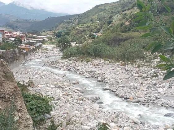 El río Motatán a su paso por el pueblo, con el cauce ancho de piedras y un hilo de agua entre ellas.