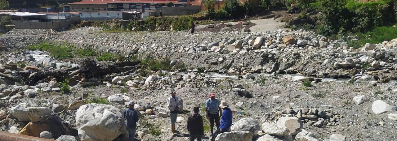 Varias personas caminando por el lecho pedregoso del río, que deja ver hasta dónde llegaba el agua.