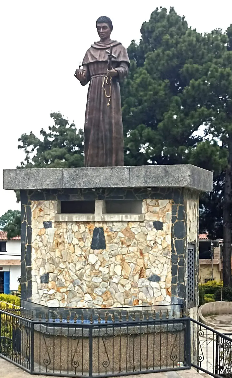 La imagen de San Benito, con hábito y rosario, sobre su pedestal forrado de piedra y cercado con reja.