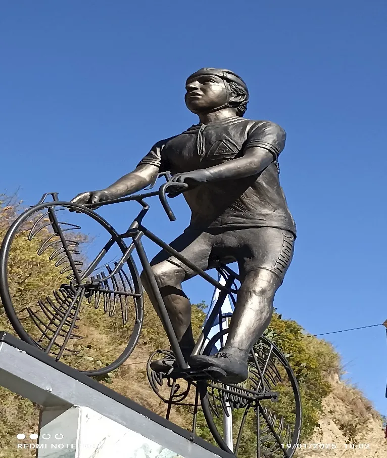 La escultura del ciclista sobre su bicicleta, contra el cielo azul.