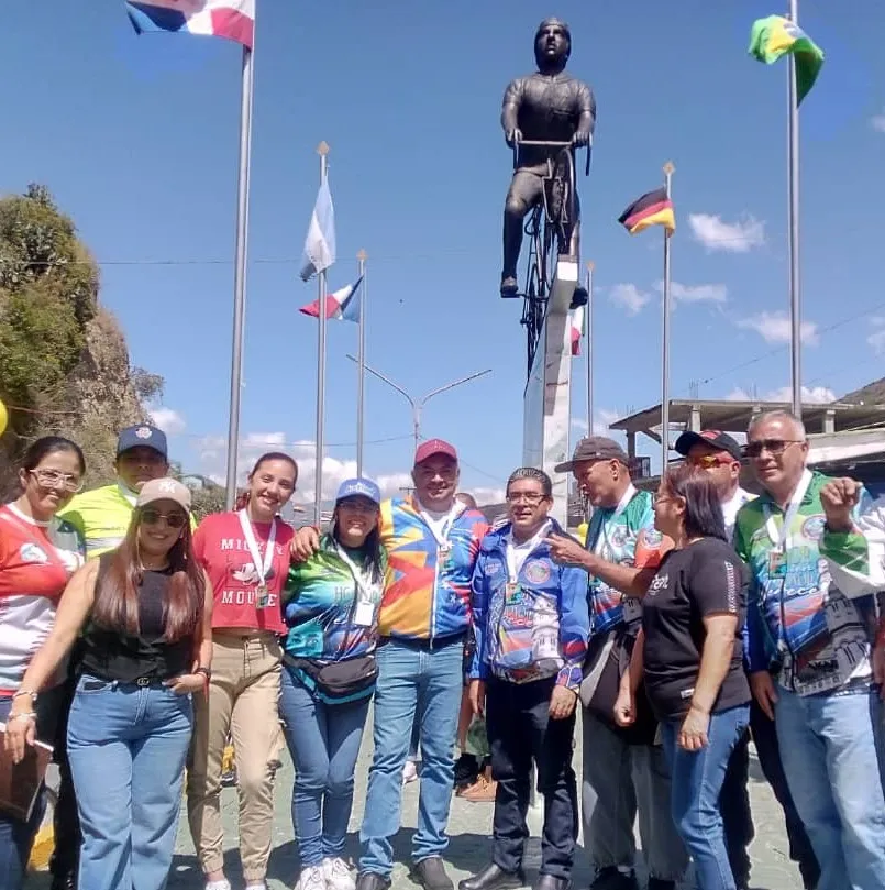 Un grupo de personas, varias con franelas de ciclismo, posa al pie del monumento.