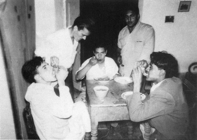 Fotografía antigua de varios jóvenes comiendo alrededor de una mesa.