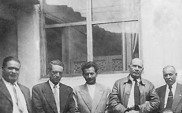 Fotografía antigua de un grupo de hombres de traje sentados en fila.