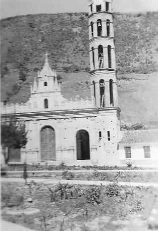 Fotografía antigua de la iglesia de Timotes con una sola torre levantada y la fachada inconclusa.