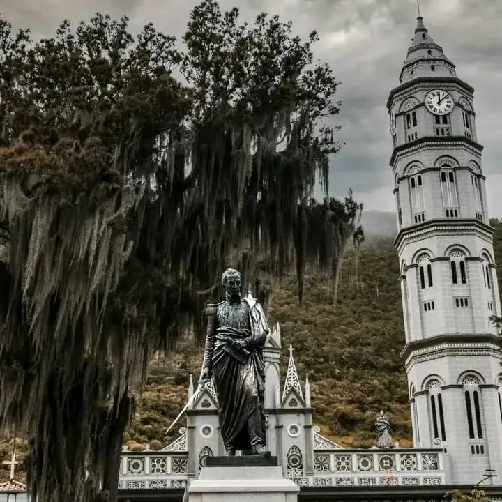 La estatua del Libertador en la plaza, con la torre del reloj de la Basílica detrás y la barba de palo colgando de los árboles.