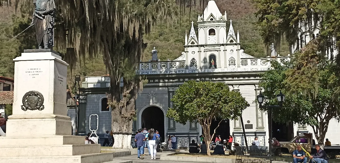 La fachada de la Basílica y su torre vistas desde la plaza, con el monumento a Bolívar entre los árboles.