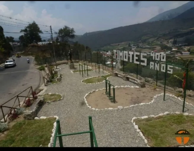 El parque mirador con el letrero «Timotes 400 años» en la ladera y el monumento al fondo, sobre la carretera.