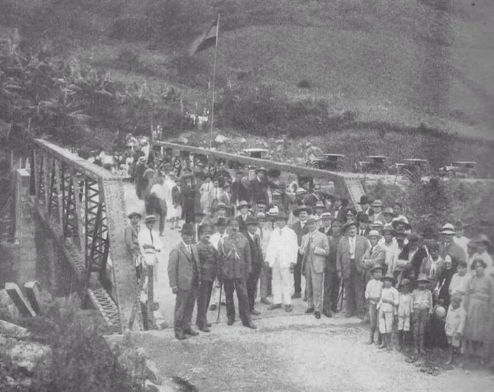 Inauguración del puente metálico: el gentío de la época posa a la entrada, con la bandera izada y los automóviles de los años veinte al otro lado.