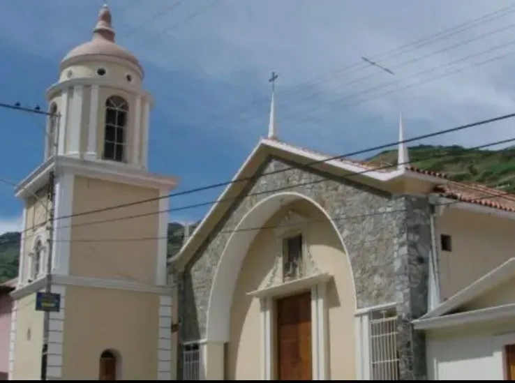 Iglesia de fachada de piedra y arco apuntado, con su torre de cúpula al costado.