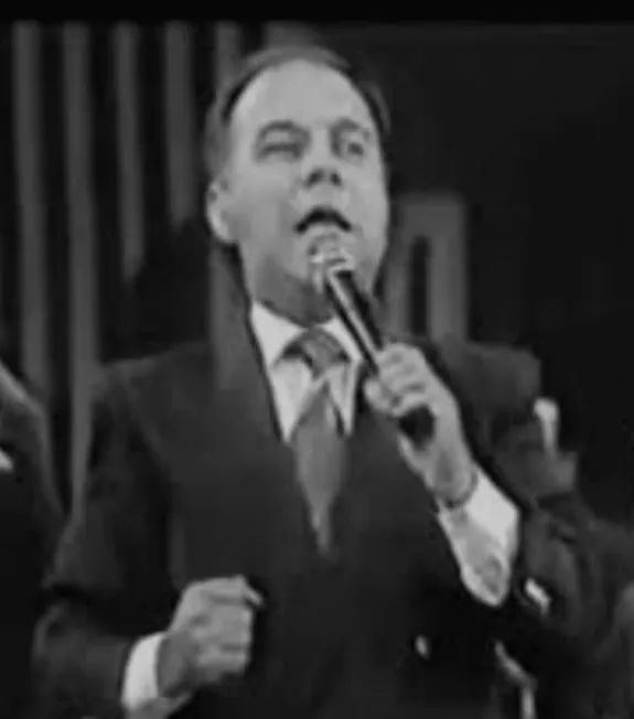 Un hombre de traje habla con energía ante el micrófono, en una imagen en blanco y negro.