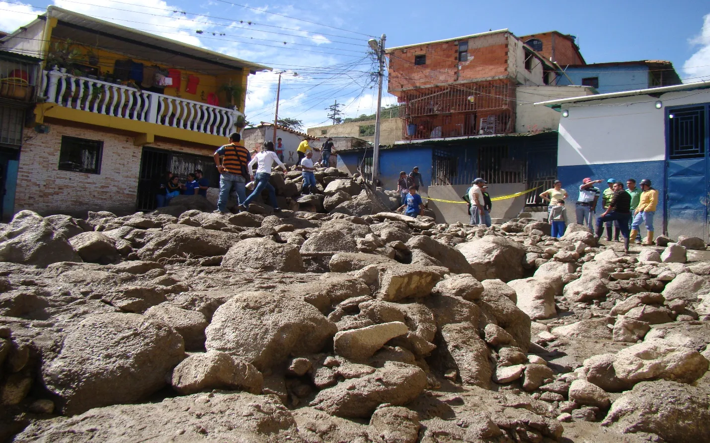 Después de la vaguada: la calle sepultada bajo un manto de piedras y barro que llega a la altura de las casas, con los vecinos asomados a mirar.