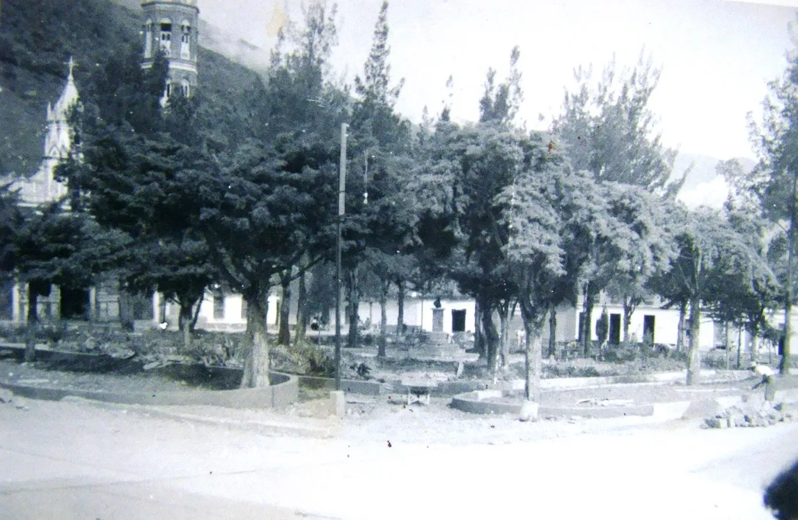 La plaza en obras, con los canteros a medio levantar y los árboles ya crecidos; detrás, la iglesia y su torre.