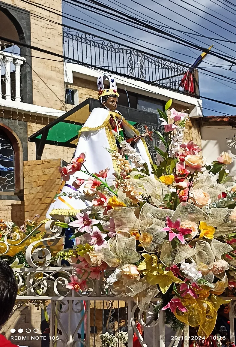 La imagen coronada de San Benito sobre las andas, entre flores y lazos, saliendo del templo.