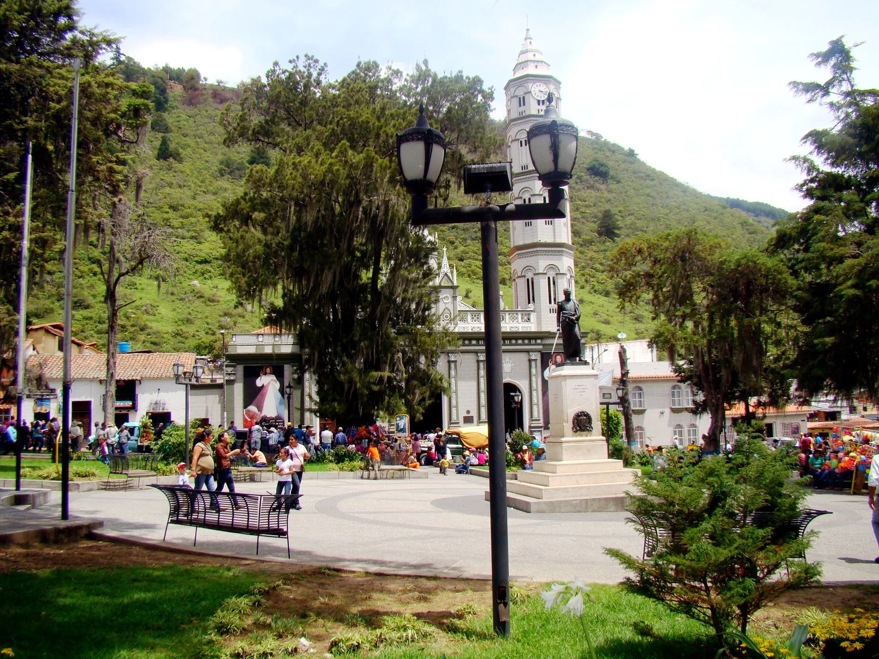 Plaza Bolívar de Timotes en día de fiesta, con la estatua del Libertador y la Basílica Menor de Santa Lucía al fondo.
