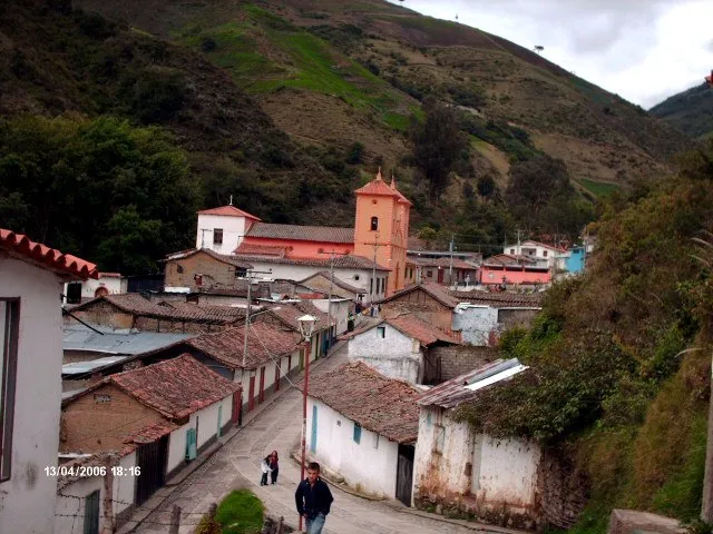 Pueblo de montaña con su templo de torre y los techos de teja, visto desde la calle en cuesta.