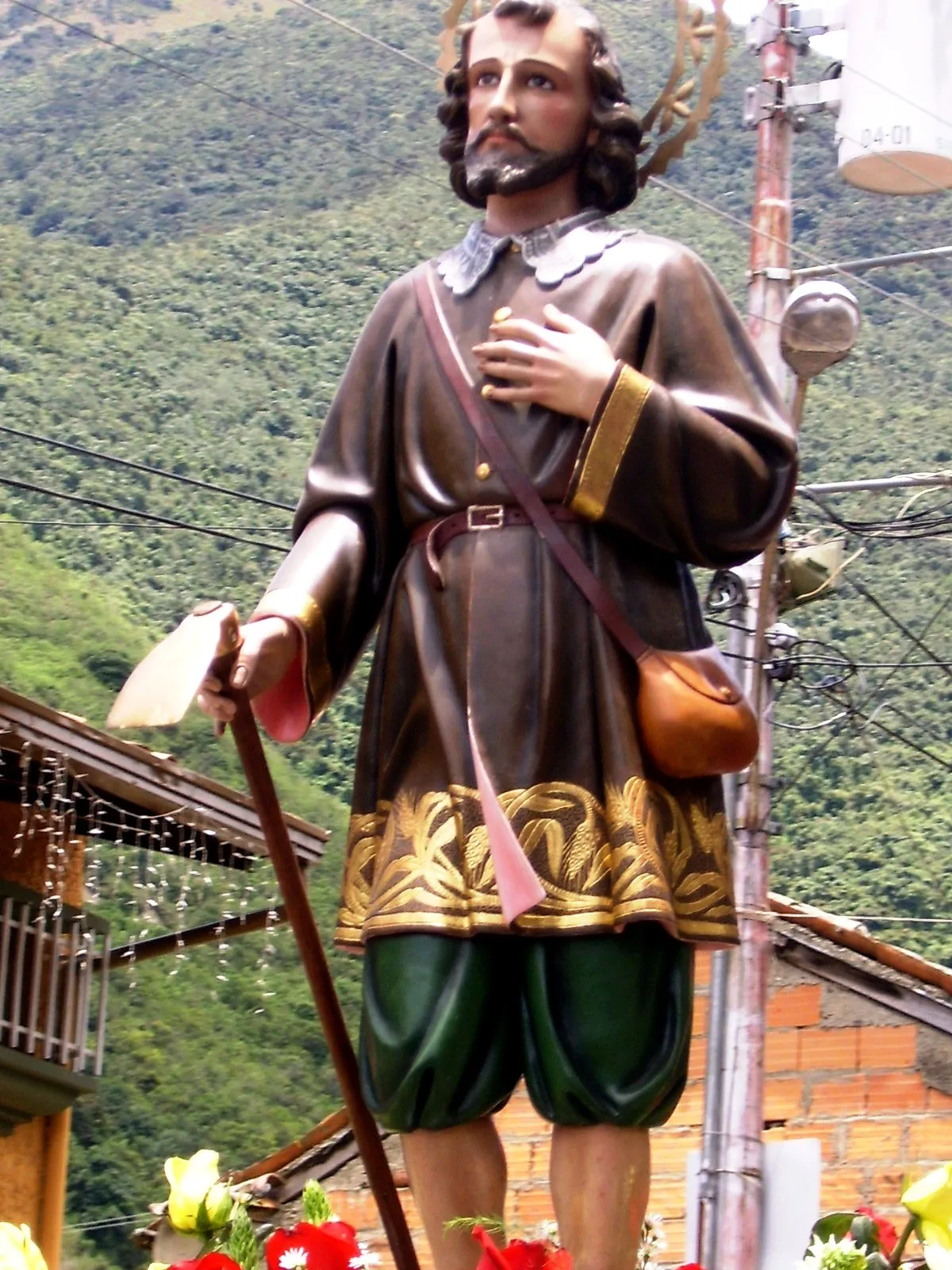 Imagen de San Isidro Labrador en la calle, con el aguijón y el morral, adornada de flores para la procesión.