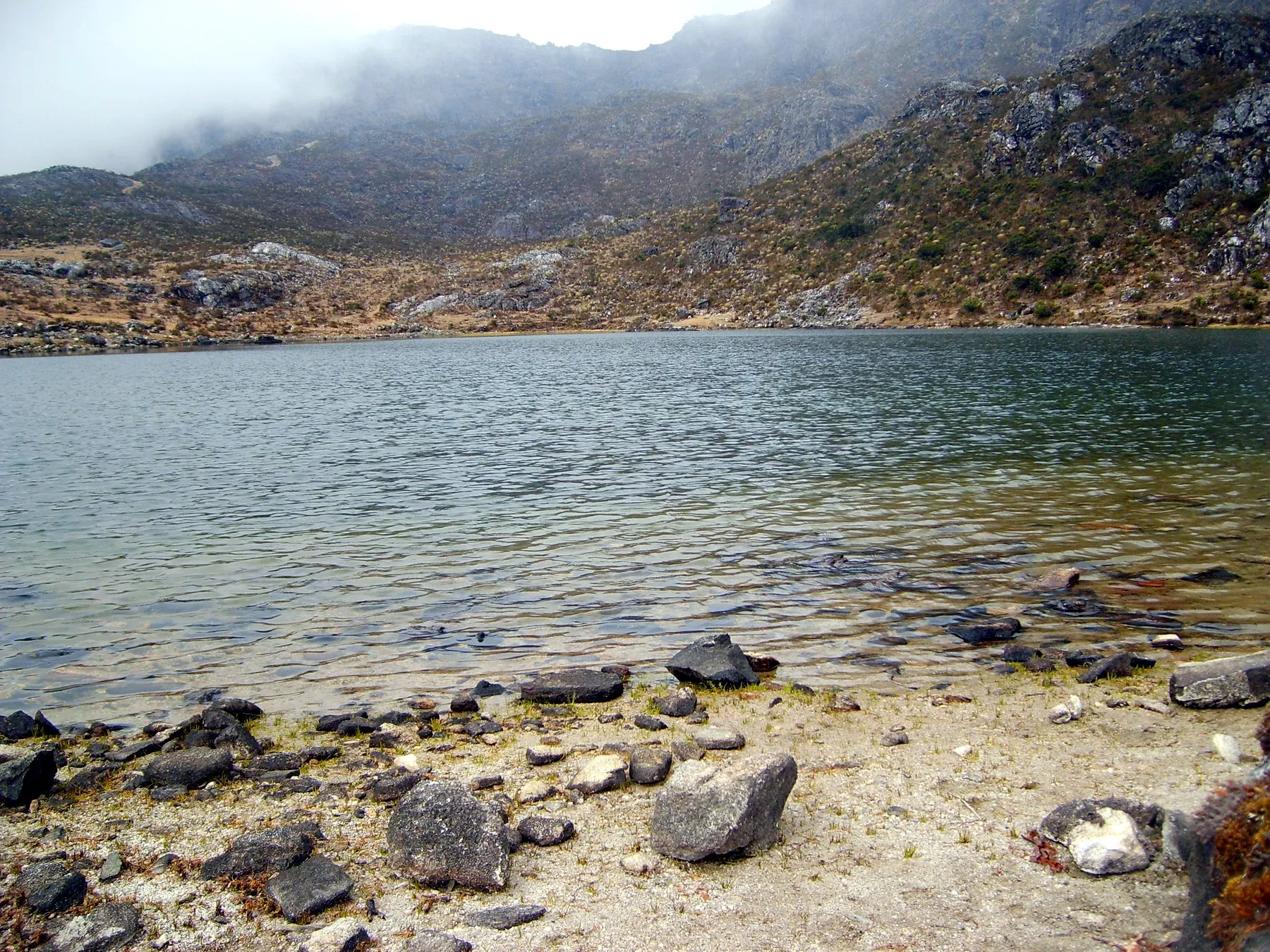 Laguna de páramo con la neblina bajando por el cerro. Sin identificar: el libro no la titula y la foto no da señas de cuál es.