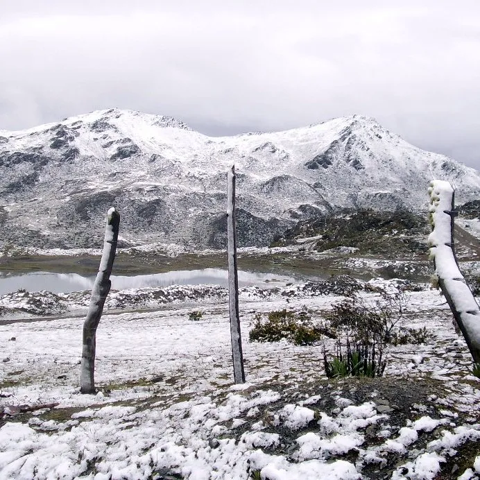Snowfall on the páramo, with the lagoon below the peaks