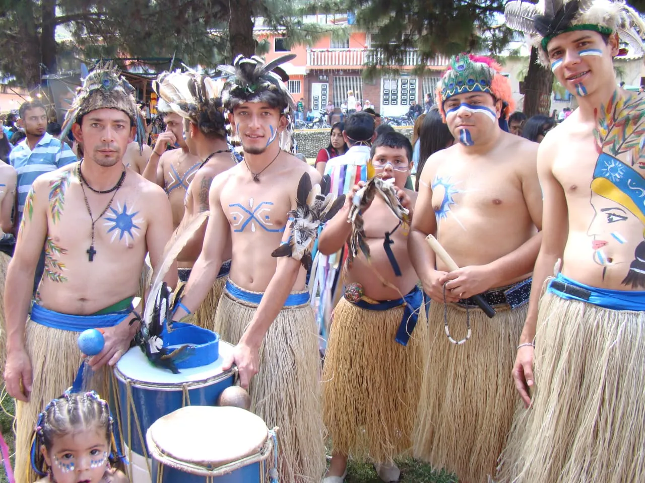Comparsa de indios: penachos de plumas, faldas de fibra, pintura corporal y tambores.