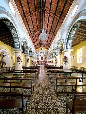 Nave de un templo hacia el altar mayor, con el artesonado de madera, los arcos decorados y el piso de mosaico. Sin identificar cuál es.