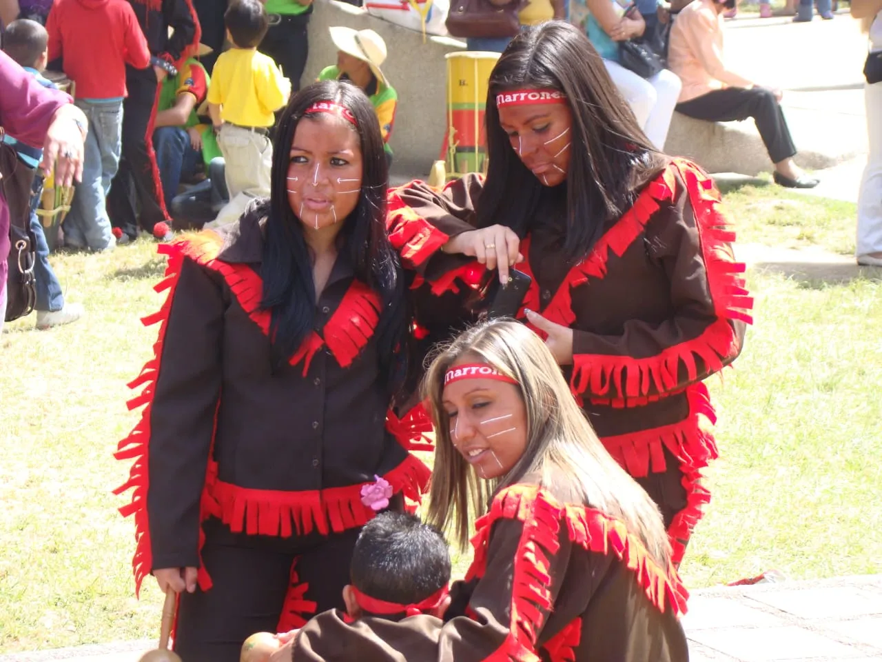 Comparsa «Marrones»: vinchas con el nombre del grupo, trajes marrones con flecos rojos y el rostro pintado con rayas blancas.
