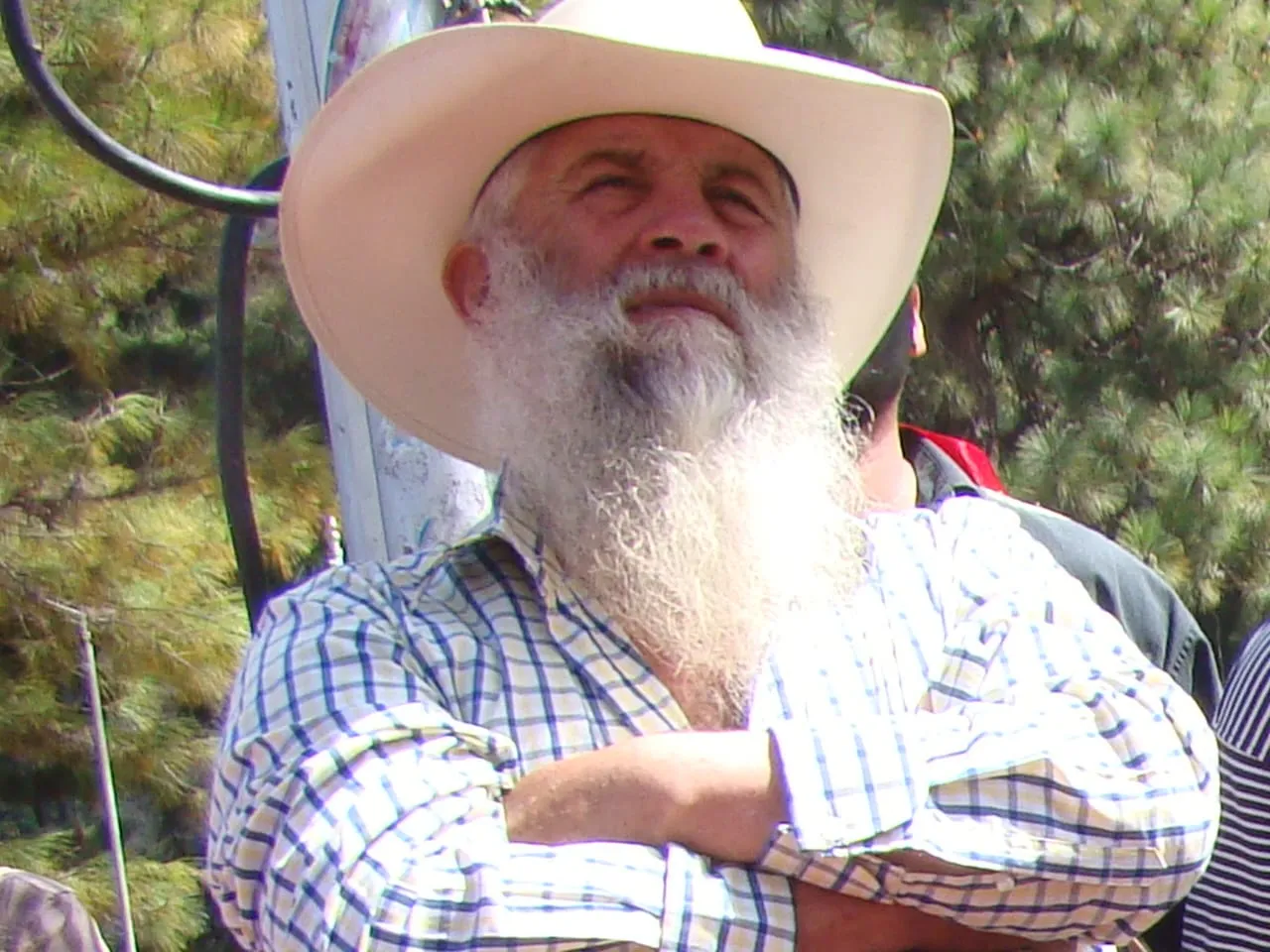 Un hombre de barba blanca y sombrero, entre el gentío de una fiesta.
