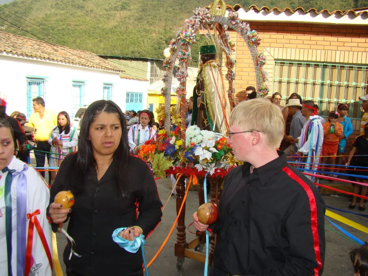 La imagen de San Benito sobre las andas, bajo un arco de flores, rodeada de los danzantes con sus maracas.