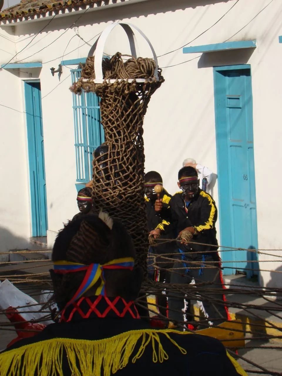 Los Negros de San Benito, de negro con flecos amarillos y la vincha tricolor, tensan los cordeles que bajan del aro: la red de mecate tejida queda colgando en el centro, frente a las puertas azules de la casa.