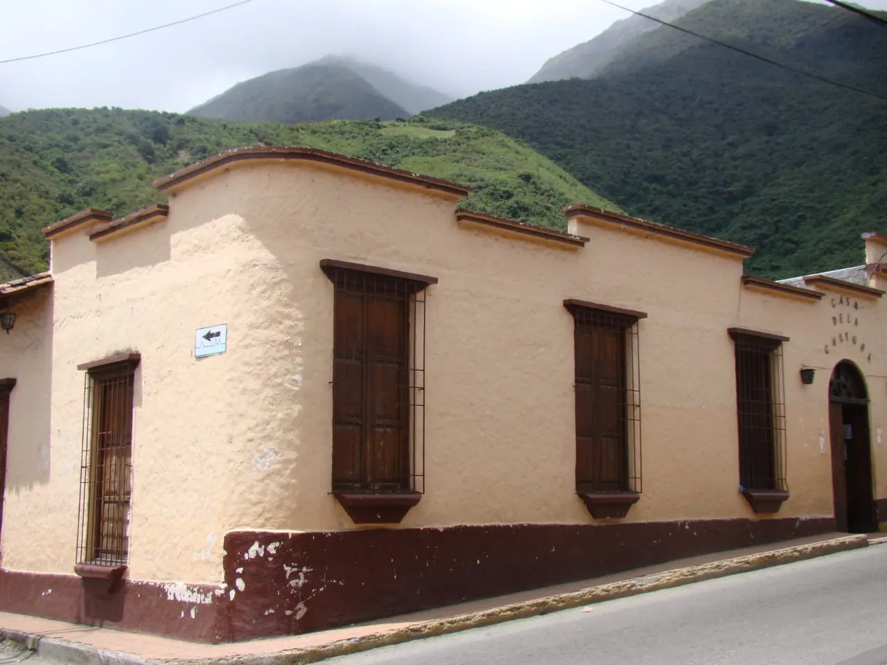 La Casa de la Cultura de Timotes desde la esquina, con su nombre en la fachada y el cerro verde detrás.