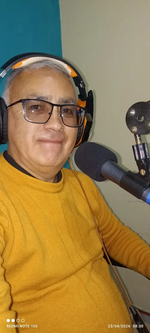 El cronista al micrófono, con los audífonos puestos, en la cabina de la emisora.