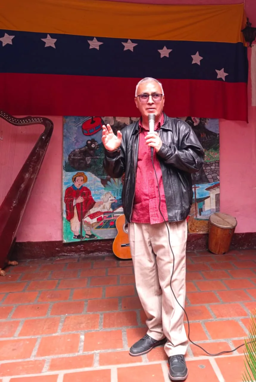El cronista habla con el micrófono en la mano ante la bandera nacional, entre el arpa, el cuatro y el tambor, en un patio de baldosas.